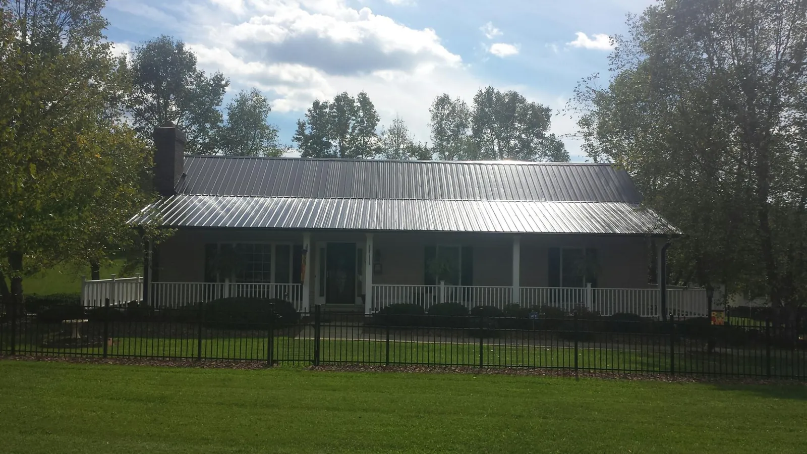 Gray metal roof on a brick ranch with a full width front porch — Gutter Guard Installation work by our crew in Mountain Home